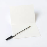 Inside of an off-white greeting card with a pen, placed on a white background