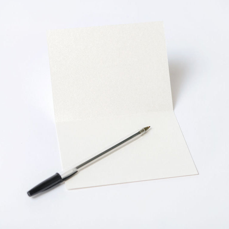 Inside of an off-white greeting card with a pen, placed on a white background