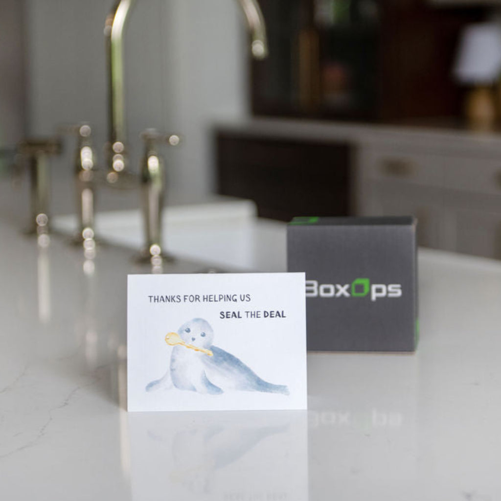BoxOps gift box on a kitchen counter with a greeting card that reads 'Thanks for helping us seal the deal'.