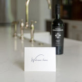 'Welcome home' greeting card on a kitchen counter with a bottle of wine.