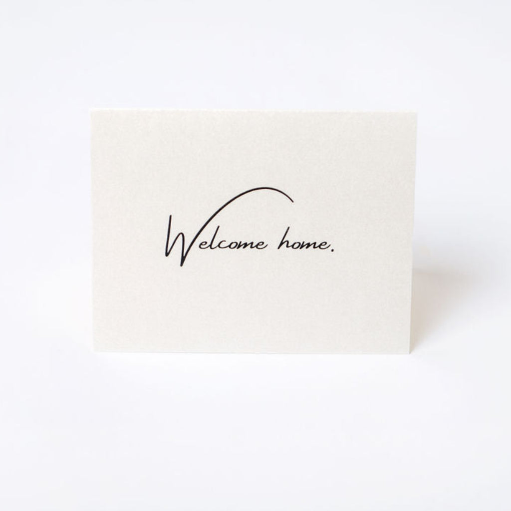 Beige premium paper card with 'Welcome home' text printed on it.