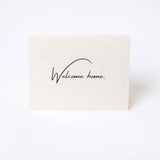 Beige premium paper card with 'Welcome home' text printed on it.