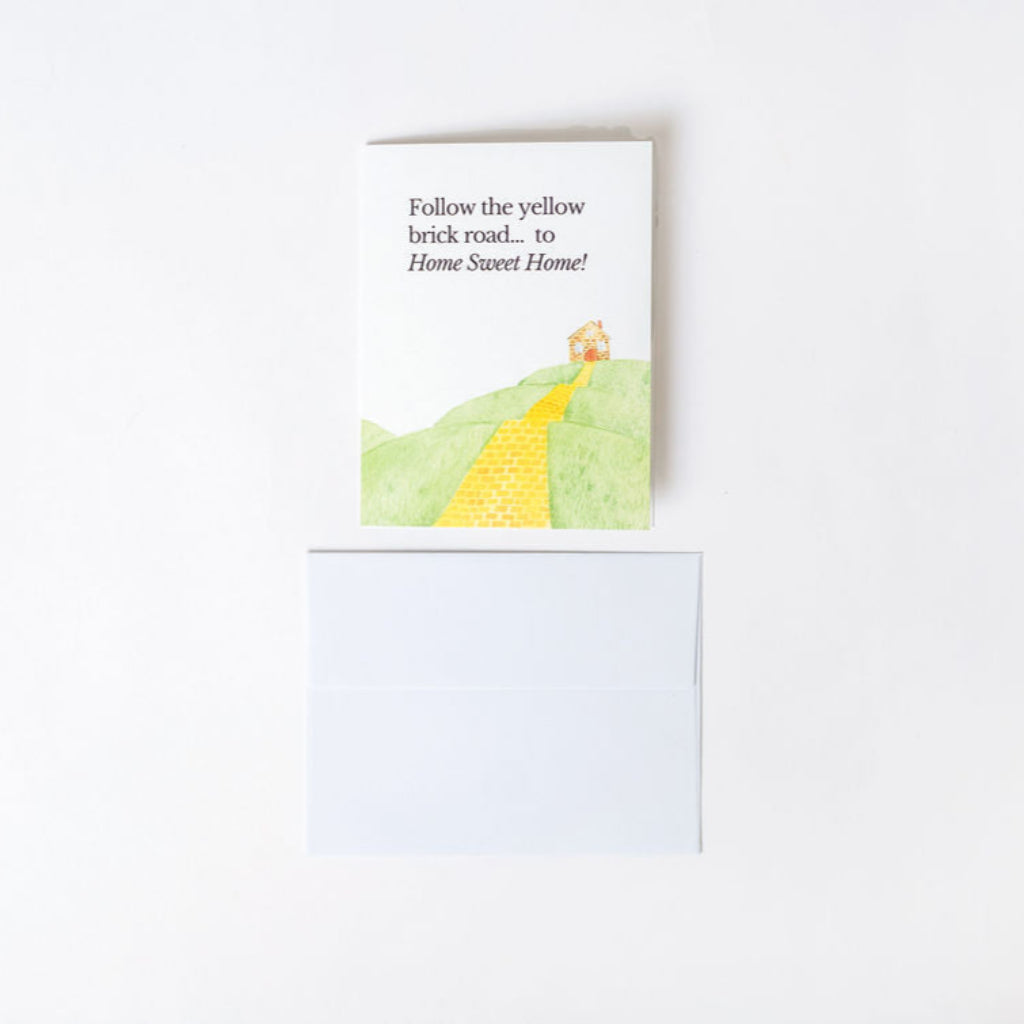 Greeting card with a yellow brick road illustration and text on a white background