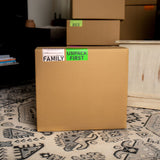 Stack of cardboard moving boxes with color coded moving box labels such as UNPACK FIRST 