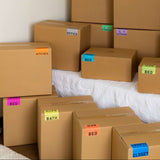 Stack of cardboard boxes with color coded labels on each box to designate rooms.