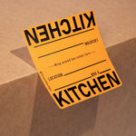 Orange 'KITCHEN' label on a cardboard box