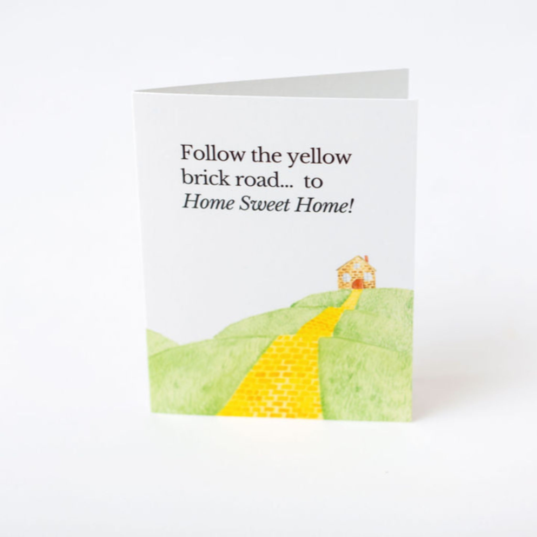 Greeting card with a yellow brick road and house illustration, text 'Follow the yellow brick road.