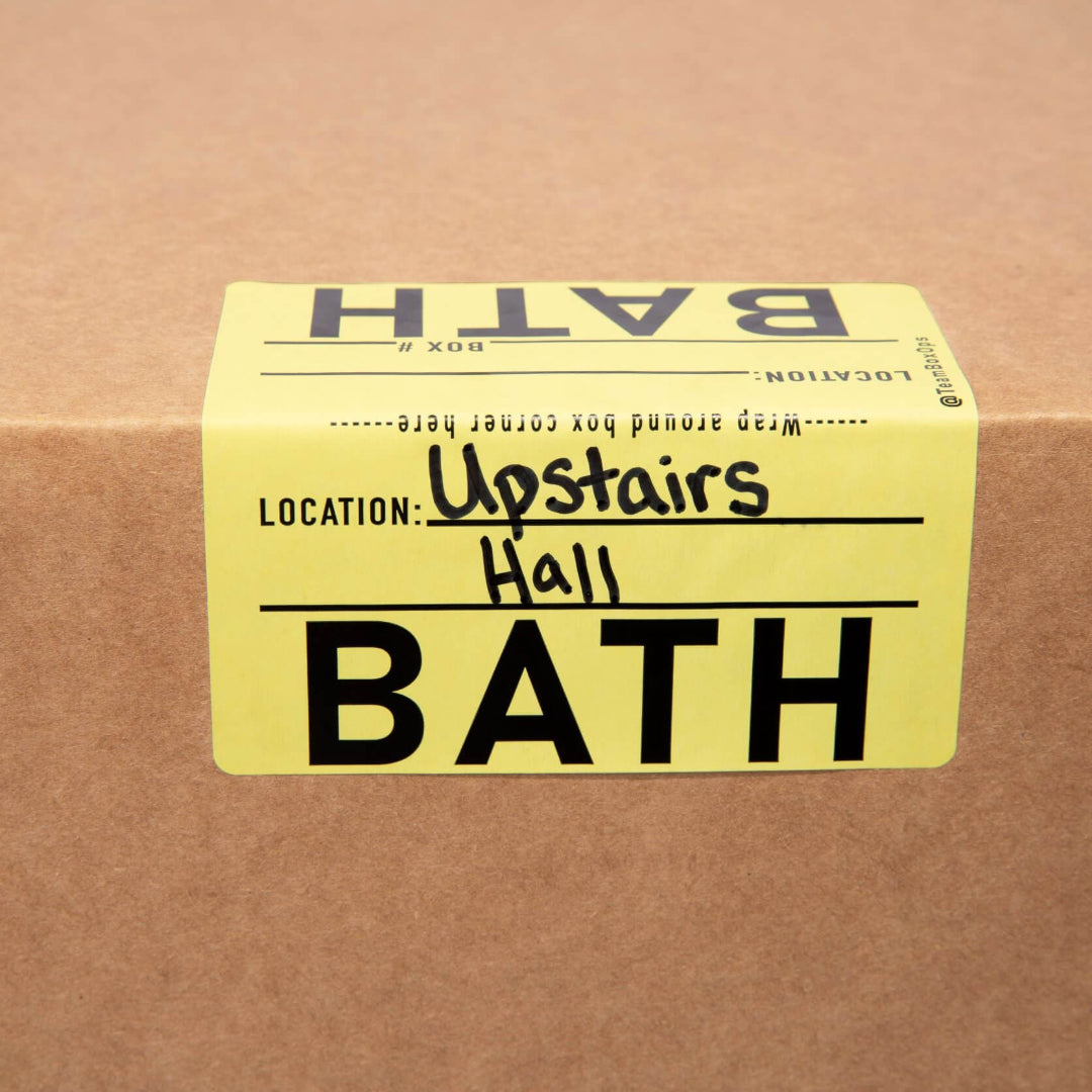 yellow bath moving sticker on cardboard box labeled "upstairs hall"